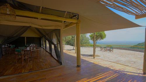 a patio with tables and chairs and a large umbrella at Mara Elatia Camp in Masai Mara