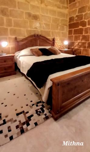 a bedroom with a large bed with a wooden frame at Il Mithna farmhouse with indoor heated jacuzzi pool in Għarb