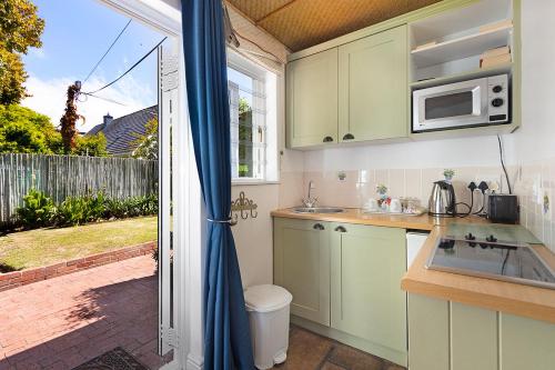 eine Küche mit einer Spüle und einer Mikrowelle in der Unterkunft Morningside Cottage in Tokai