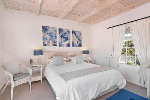 a white bedroom with a large bed and a window at Morningside Cottage in Tokai