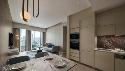 a kitchen and living room with a table and chairs at Pan Pacific Serviced Suites Kuala Lumpur in Kuala Lumpur