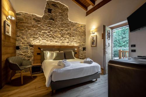 アオスタにあるLes Plaisirs d'Antanの石壁のベッドルーム1室(大型ベッド1台付)
