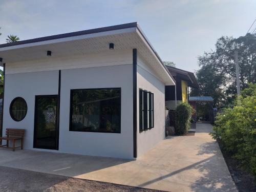 a small white building with black windows on it at Aroonsri Thara in Ratchaburi