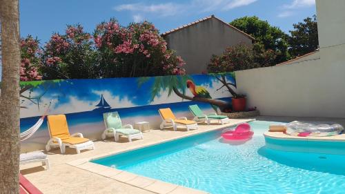 une piscine avec des chaises et un mur orné d'une fresque murale. dans l'établissement chambre chez corinne et bernard, à Cazouls-lès-Béziers
