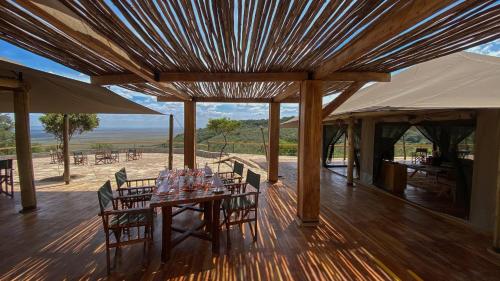 a wooden deck with a table with chairs and an umbrella at Mara Elatia Camp in Masai Mara