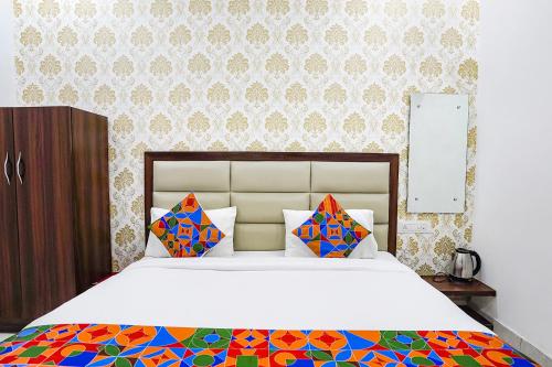 a bedroom with a large white bed with colorful pillows at FabHotel Swess in Agra