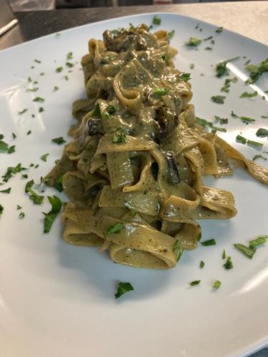 a white plate of pasta with mushrooms and sauce at Sorrento Hotel & Restaurant in Cambridge