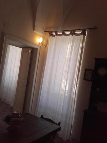a room with a window with white curtains and a table at Antica Via delle Aie in Ruffano