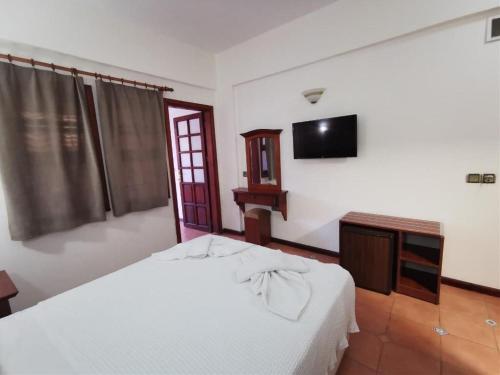 a bedroom with a white bed and a television at Club Pink Palace Hotel in Oludeniz