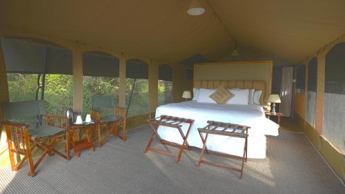 a bedroom with a bed and two chairs and a table at Mara Elatia Camp in Masai Mara