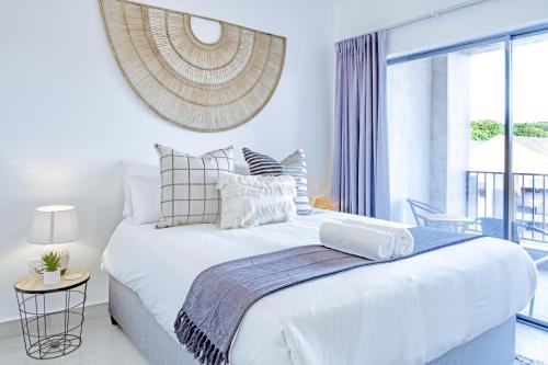 a white bedroom with a large bed and a window at Ballito Village Luxury Apartments in Ballito