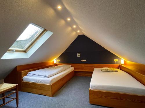 a attic room with two beds and a window at Bungalow "Sillo´s Hüs" in Nebel