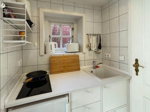 a white kitchen with a sink and a window at Bungalow "Sillo´s Hüs" in Nebel