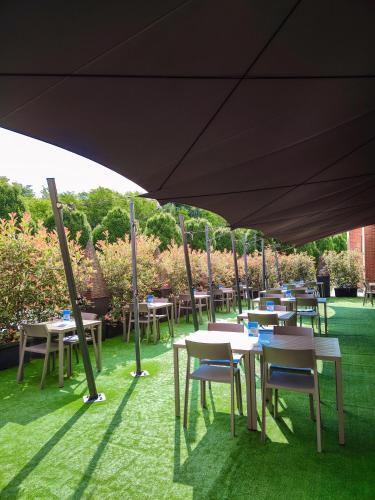 a group of tables and chairs under an umbrella at Just Hotel Lomazzo Fiera in Lomazzo