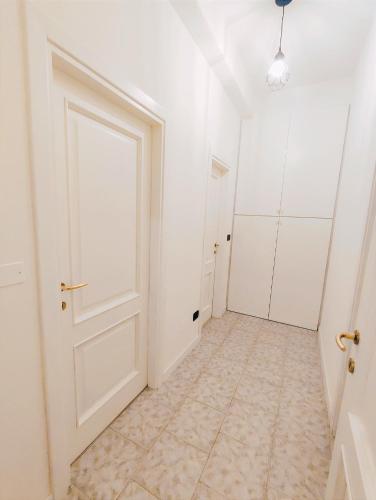 einen leeren Flur mit weißer Tür und Fliesenboden in der Unterkunft Stanza privata a Brescia in Brescia