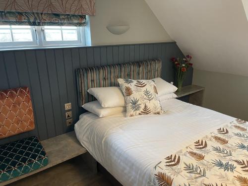 a bedroom with a large bed with a white comforter at The White Horse Hotel and Luxury Shepherds Huts in Eye
