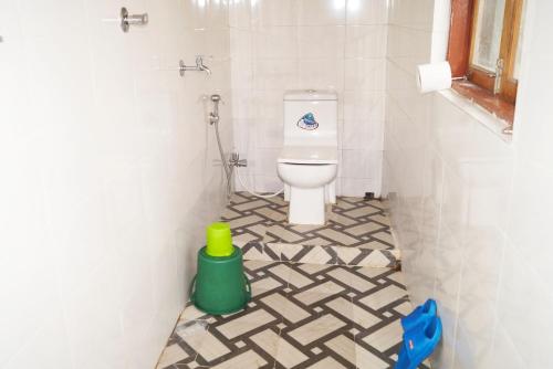a bathroom with a toilet in a tiled floor at Yumasham Homestay in Darjeeling