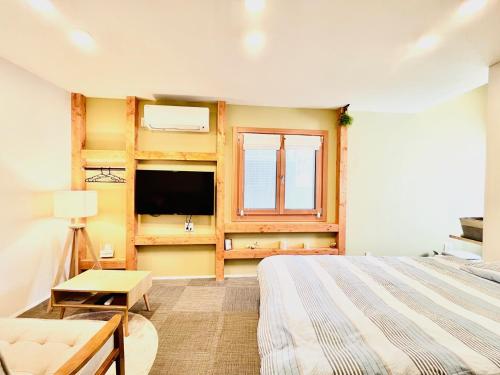 1 dormitorio con 1 cama, TV y ventana en 池袋Apila en Tokio