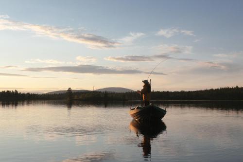 a man is fishing on a boat on a lake at Hotell Bruksvallsliden in Bruksvallarna