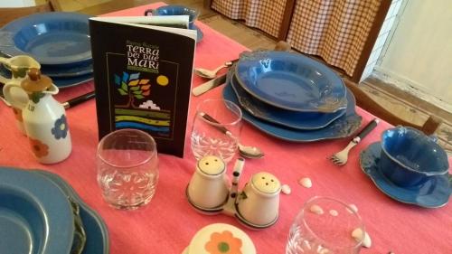 a table with blue plates and glasses and a book at Antica Via delle Aie in Ruffano