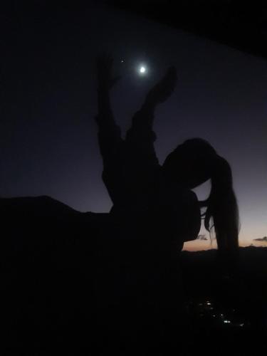 a woman dancing in the dark with the moon in the background at Cabana do Camelo in São Bento do Sapucaí