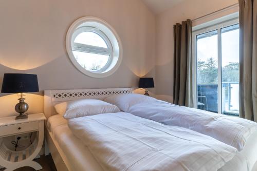 1 cama blanca en un dormitorio con ventana en Penthouse Penthouse Skipperhuset, en Sankt Peter-Ording