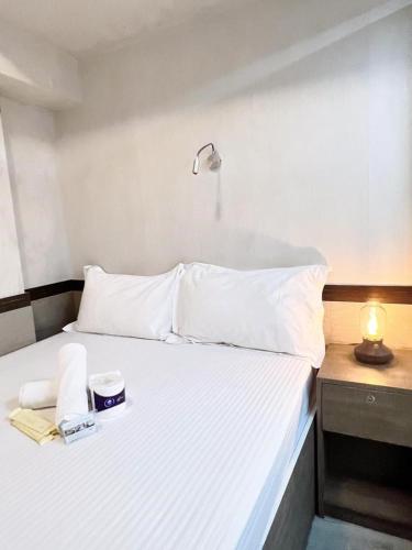 a white bed with a lamp and a book on it at SAAN INN in Hong Kong