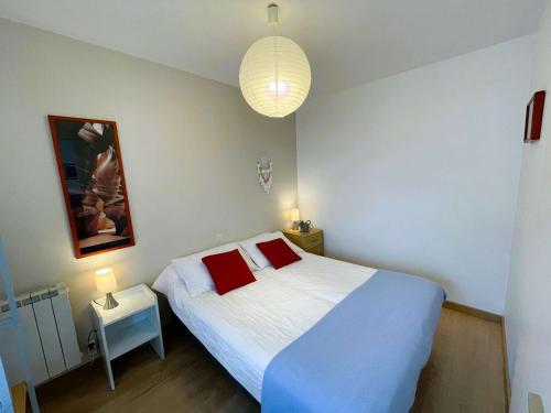 a bedroom with a white bed with red pillows at Appartement 3 étoiles avec Wifi à Perros-Guirec - FR-1-542-42 in Perros-Guirec
