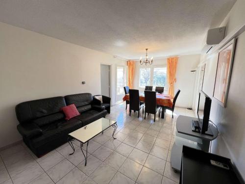un salon avec un canapé noir et une table dans l'établissement Appartement T3 Climatisé, 2 Chambres, Balcon, Parking, Proche Plage, Lave-linge - FR-1-702-22, au Cap d'Agde