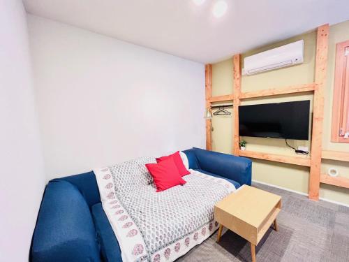 a bedroom with a blue couch with a red pillow at 池袋Apila in Tokyo
