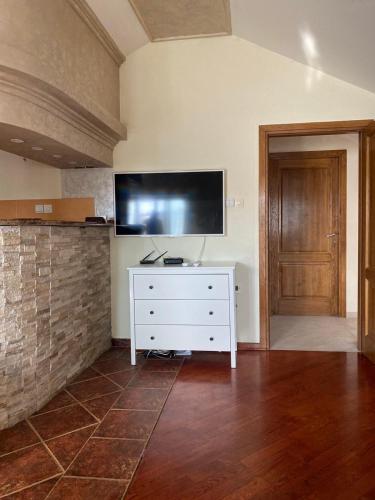 a living room with a white dresser with a flat screen tv at Apartman Jaca in Mrčevac