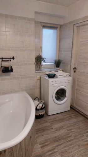 a bathroom with a tub and a washing machine at Apartament Mar&Mel in Głuchołazy