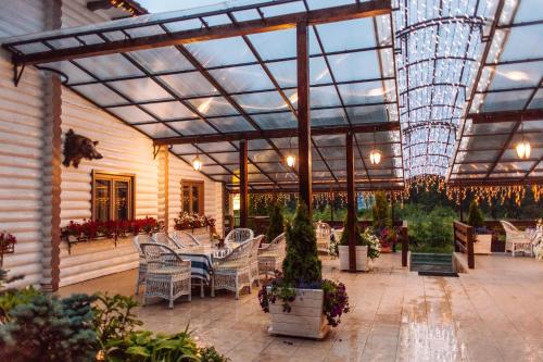 a patio with white chairs and a glass ceiling at Hotel Vedmezhyi Dvir in Bukovel