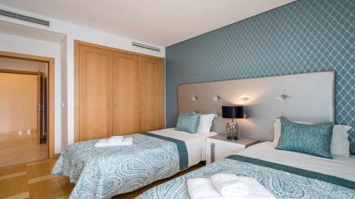 een hotelkamer met 2 bedden en blauwe muren bij Marina Vilamoura Aquamar 220 By Vilamoura Sun in Quarteira