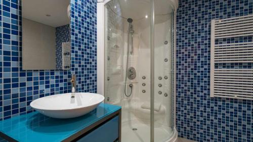 ein blau gefliestes Bad mit einem Waschbecken und einer Dusche in der Unterkunft Marina Vilamoura Aquamar 220 By Vilamoura Sun in Quarteira
