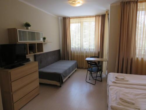 a bedroom with a bed and a tv and a table at Rivendell Apartments Borovets Gardens Deluxe Studios in Borovets