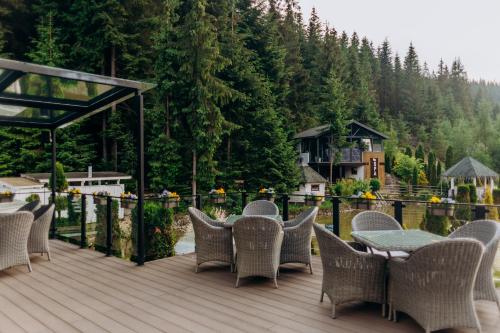 a deck with wicker chairs and a table with a view at Hotel Vedmezhyi Dvir in Bukovel