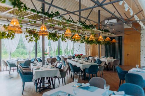 un comedor con mesas, sillas y lámparas de araña en Hotel Vedmezhyi Dvir, en Bukovel