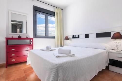 a bedroom with a white bed and a red dresser at Las Hélices San José Cabo de Gata in San José