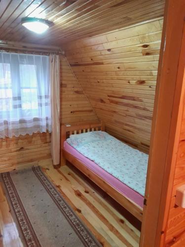 Cabaña de madera con cama en una habitación en Domek Leśny Klimat, en Serpelice