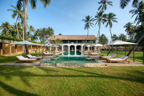 a house with a swimming pool and palm trees at Kayaam House in Tangalle