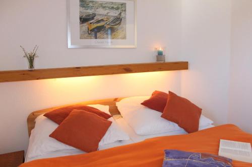 a bed with orange and white pillows in a room at "Appartement 6 - Feriennest" - ab sofort mit W-LAN in Grömitz