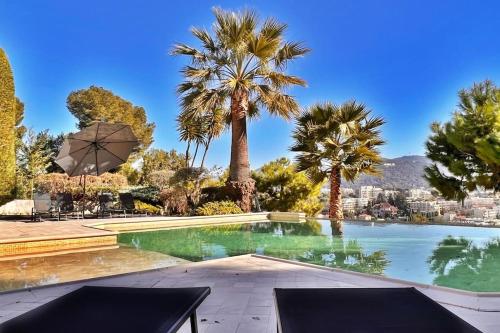 a swimming pool with palm trees and a city at La Villa Gairaut in Nice