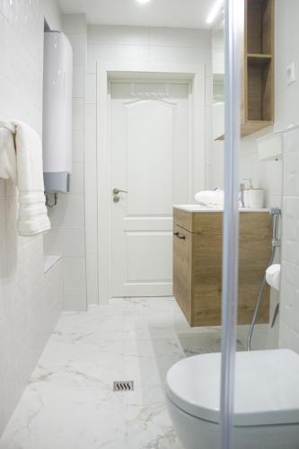 a white bathroom with a toilet and a sink at Grand Relax Cape Cod by RV Apartments in Varna City