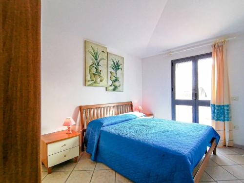 Cala Francese Apartments في كابو تيستا: غرفة نوم بسرير ازرق ونافذة