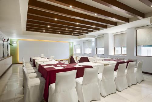 a dining room with a long table and white chairs at Wyndham Garden Obregon in Ciudad Obregón