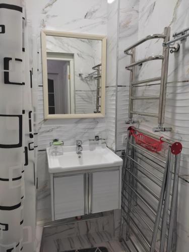 uma casa de banho branca com um lavatório e um espelho em Квартира в новом жилом комплексе Mega Tower em Tashkent