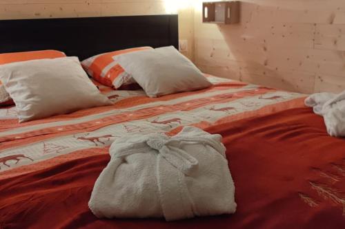 a bed with an orange blanket and white pillows at Chez Laurette in Frémifontaine
