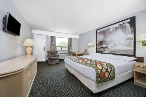 a hotel room with a large bed and a desk at Super 8 by Wyndham Niagara Falls North in Niagara Falls