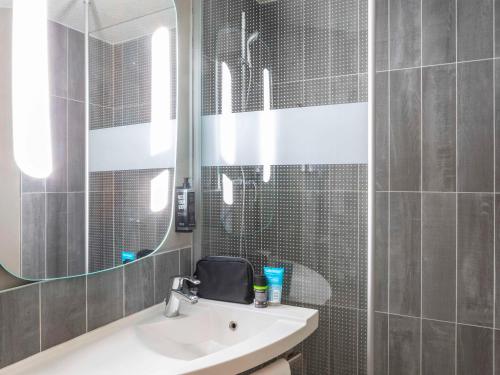 La salle de bains est pourvue d'un lavabo et d'un miroir. dans l'établissement ibis Paris porte de Bercy, à Charenton-le-Pont